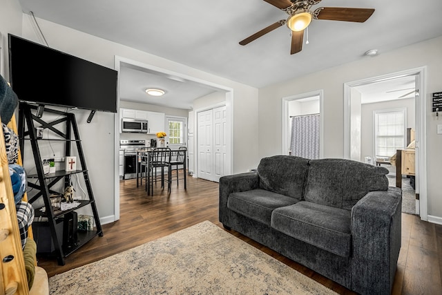 living room with dark hardwood / wood-style flooring, a wealth of natural light, and ceiling fan