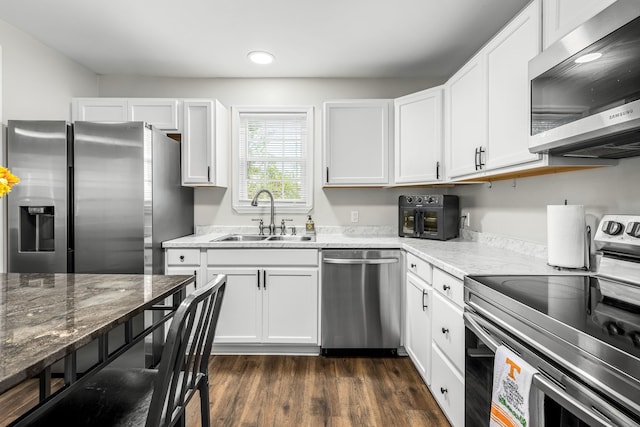 kitchen featuring white cabinetry, sink, dark hardwood / wood-style flooring, light stone countertops, and stainless steel appliances