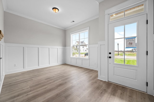 doorway to outside featuring a wealth of natural light, ornamental molding, and light hardwood / wood-style flooring