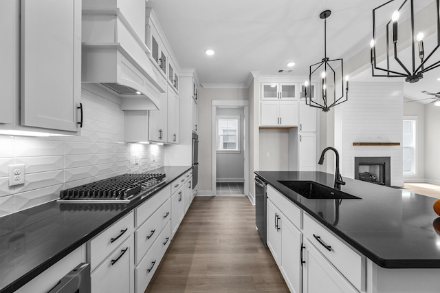 kitchen with sink, custom range hood, a fireplace, white cabinets, and dark wood-type flooring