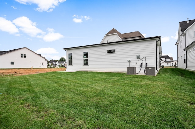 rear view of house featuring central AC unit and a lawn