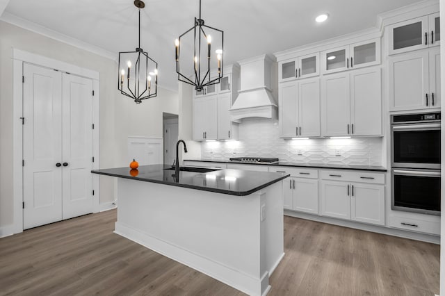 kitchen with white cabinetry, hanging light fixtures, a kitchen island with sink, and stainless steel appliances