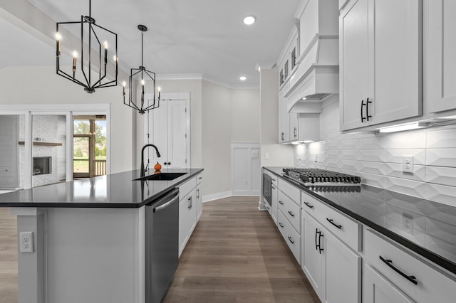 kitchen featuring stainless steel appliances, sink, white cabinets, custom exhaust hood, and a kitchen island with sink