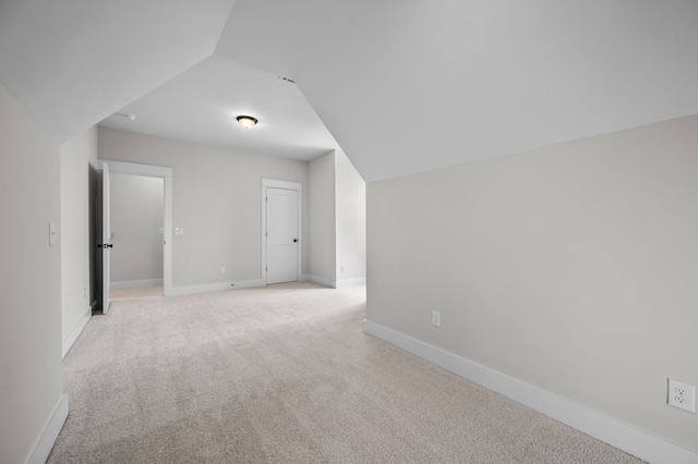 additional living space with light colored carpet and vaulted ceiling