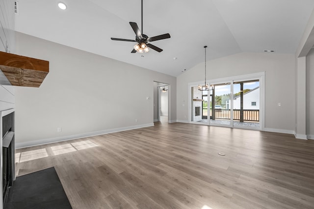 unfurnished living room featuring ceiling fan with notable chandelier, light hardwood / wood-style floors, and vaulted ceiling