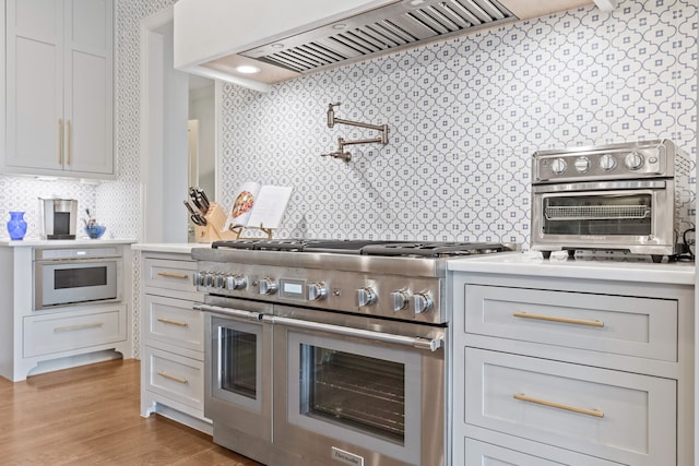 kitchen featuring range with two ovens, exhaust hood, and light hardwood / wood-style flooring