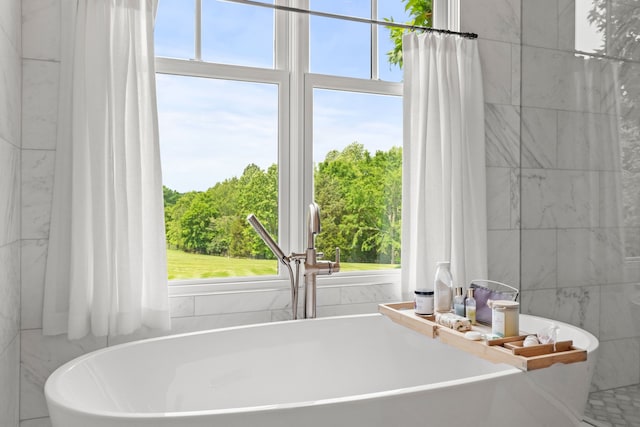 bathroom with a bathtub, a wealth of natural light, and tile walls