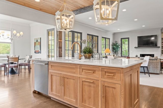 kitchen with a brick fireplace, a center island with sink, sink, wooden ceiling, and pendant lighting