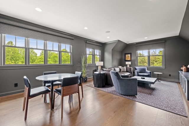 interior space with a wealth of natural light, crown molding, vaulted ceiling, and light hardwood / wood-style floors