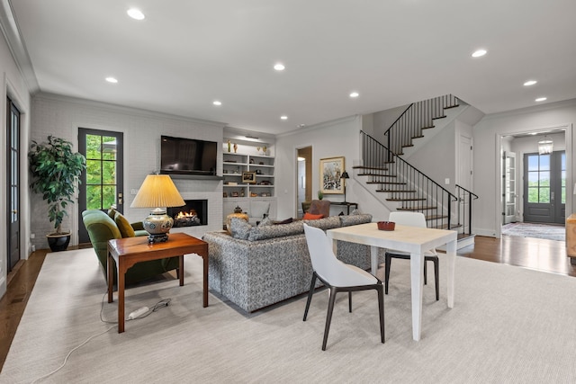 living room with a fireplace, light hardwood / wood-style floors, and crown molding