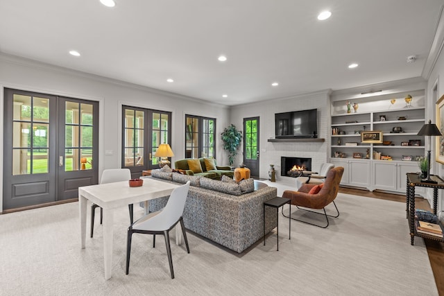 living room with light wood-type flooring, french doors, ornamental molding, and a brick fireplace