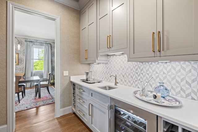 kitchen featuring beverage cooler, sink, gray cabinets, dark hardwood / wood-style floors, and crown molding