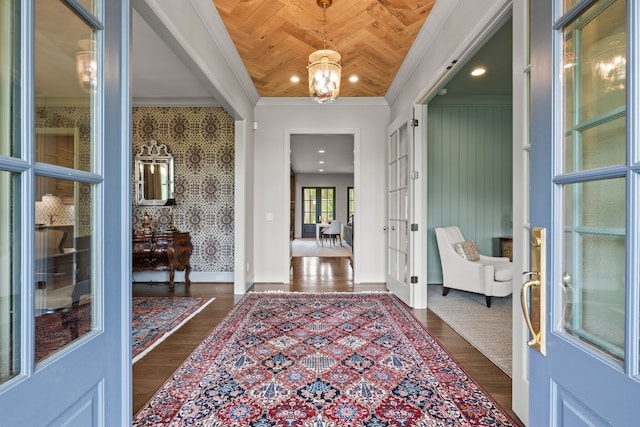 foyer entrance with a notable chandelier, dark hardwood / wood-style floors, crown molding, and wooden ceiling