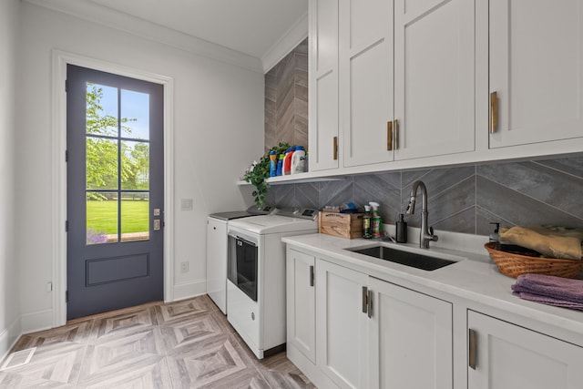 washroom with light parquet floors, crown molding, washer and clothes dryer, cabinets, and sink