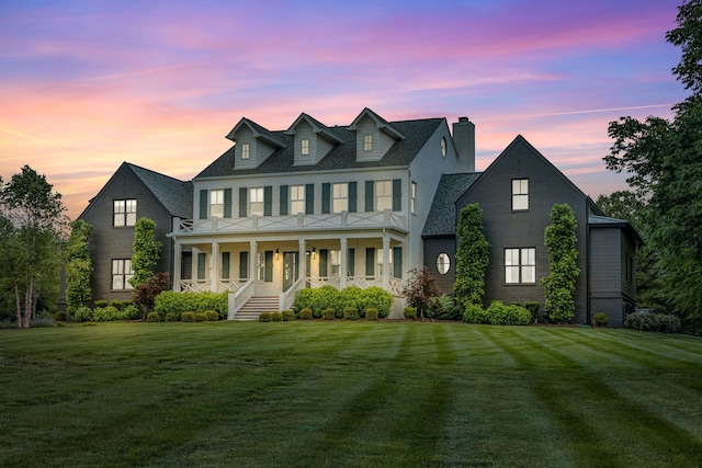 colonial inspired home featuring a porch and a lawn