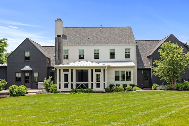 rear view of house with a lawn and a sunroom