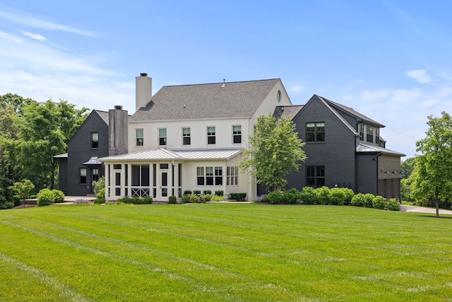 rear view of property featuring a lawn and a sunroom