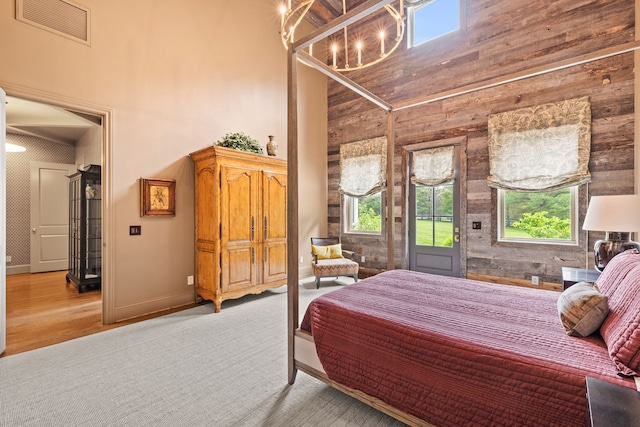 bedroom with a towering ceiling, wooden walls, and light hardwood / wood-style flooring