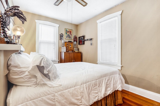bedroom featuring ceiling fan, baseboards, and wood finished floors