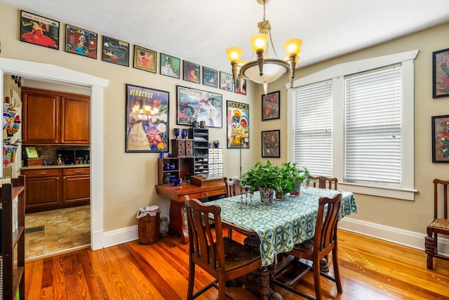 dining space featuring wood finished floors, baseboards, and a chandelier
