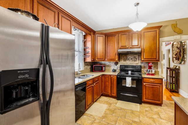 kitchen featuring tasteful backsplash, under cabinet range hood, decorative light fixtures, black appliances, and a sink