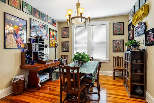 dining area with hardwood / wood-style floors, baseboards, and a chandelier