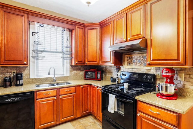 kitchen featuring tasteful backsplash, light stone countertops, under cabinet range hood, black appliances, and a sink