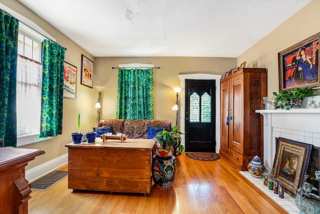foyer entrance featuring visible vents, a fireplace, a textured ceiling, and wood finished floors