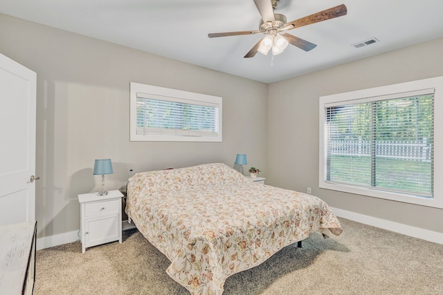 bedroom with light carpet, multiple windows, and ceiling fan