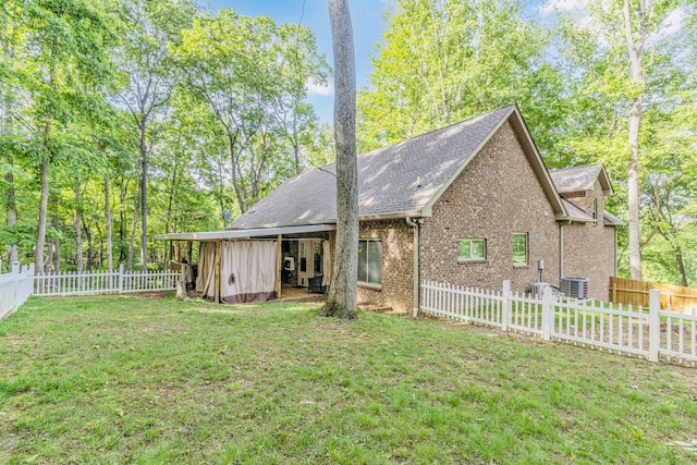 back of property featuring cooling unit and a yard