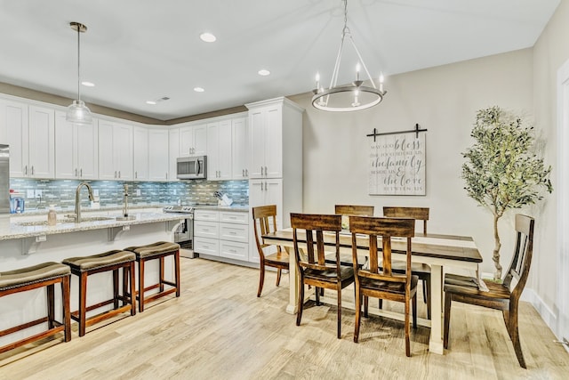 kitchen featuring appliances with stainless steel finishes, light stone countertops, hanging light fixtures, white cabinets, and a barn door