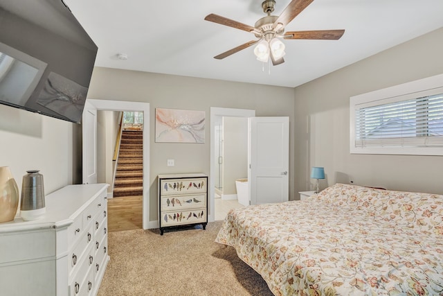 bedroom with light colored carpet, ceiling fan, and ensuite bath