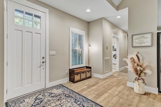 foyer entrance with light hardwood / wood-style floors and vaulted ceiling