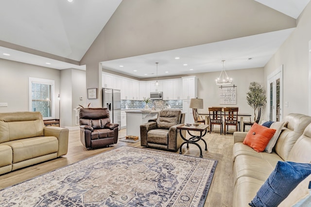 living room with light wood-type flooring, a chandelier, and high vaulted ceiling