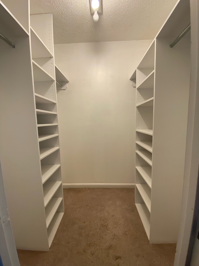 walk in closet featuring dark carpet