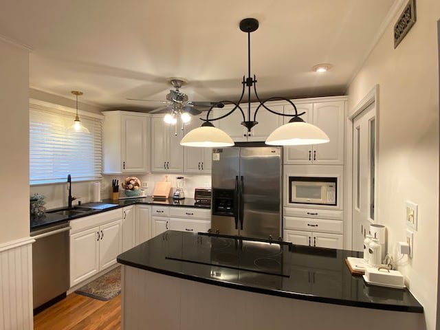 kitchen with sink, white cabinetry, stainless steel appliances, and hanging light fixtures