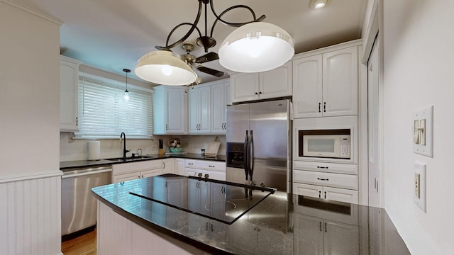 kitchen with appliances with stainless steel finishes, sink, pendant lighting, light hardwood / wood-style flooring, and white cabinets