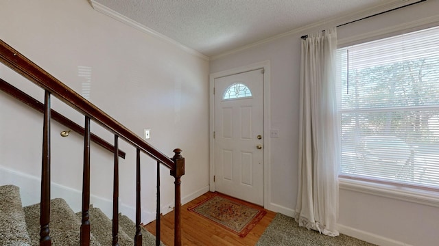 foyer entrance featuring hardwood / wood-style flooring, crown molding, and a textured ceiling