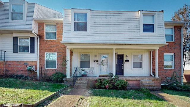 townhome / multi-family property featuring a front lawn and covered porch