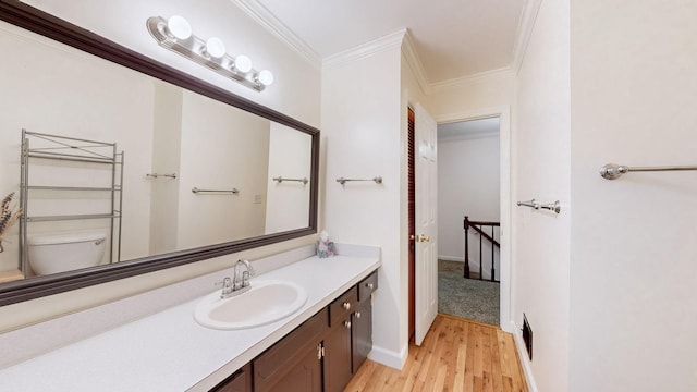 bathroom featuring vanity, toilet, wood-type flooring, and ornamental molding