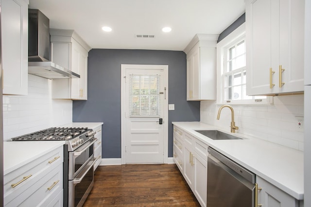 kitchen with stainless steel appliances, dark hardwood / wood-style flooring, sink, wall chimney range hood, and white cabinetry