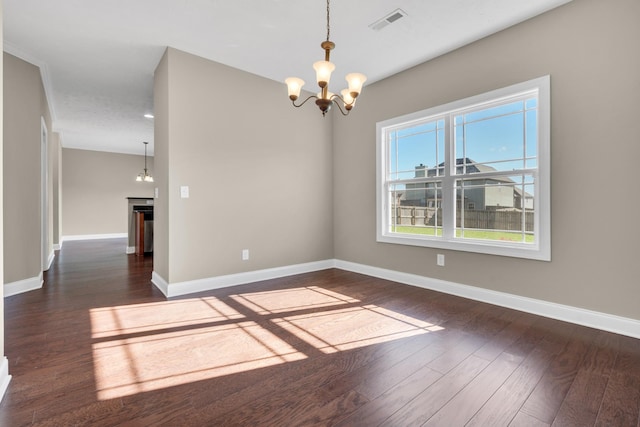 spare room featuring dark hardwood / wood-style floors and a chandelier