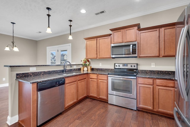 kitchen with pendant lighting, sink, dark stone countertops, stainless steel appliances, and dark wood-type flooring