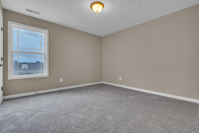 carpeted empty room featuring a textured ceiling