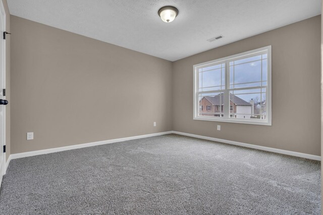 carpeted empty room with a textured ceiling