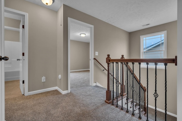 hallway featuring light colored carpet and a textured ceiling