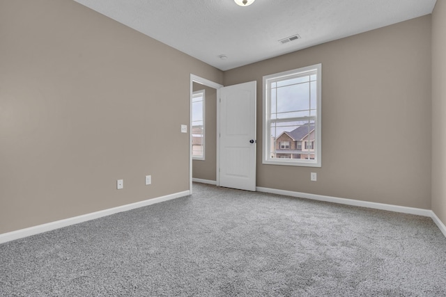 carpeted spare room with a textured ceiling