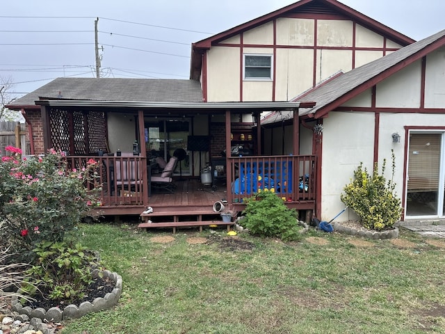 back of property featuring a wooden deck and a lawn