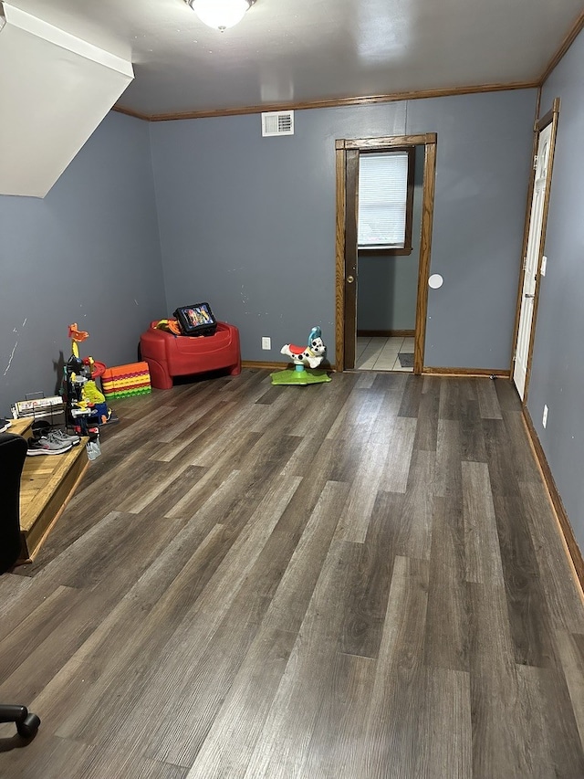 game room featuring wood-type flooring, vaulted ceiling, and crown molding