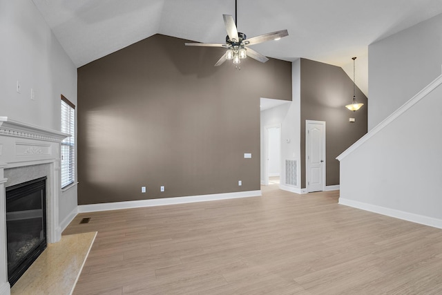 unfurnished living room with ceiling fan, high vaulted ceiling, a fireplace, and light hardwood / wood-style floors